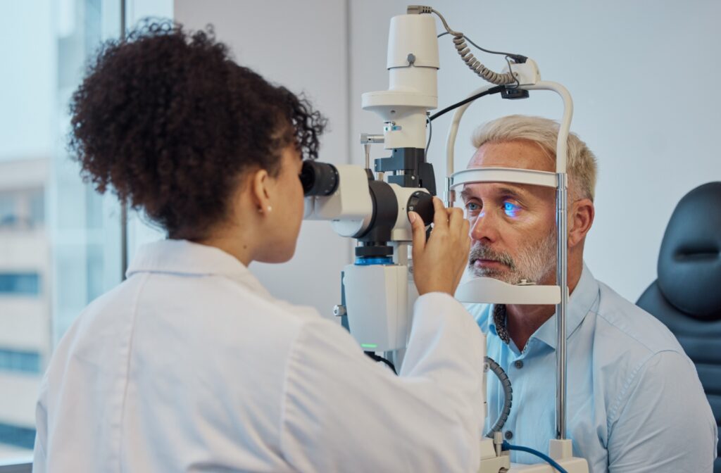 An optometrist carefully examining a senior man's eyes during a regular eye exam.