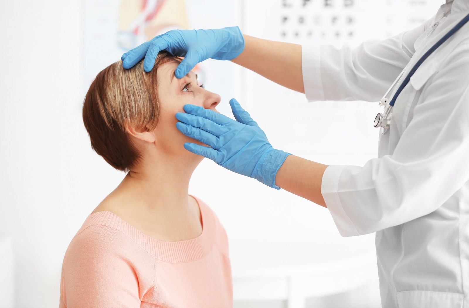 An eye doctor wearing gloves examining a person's eyes.
