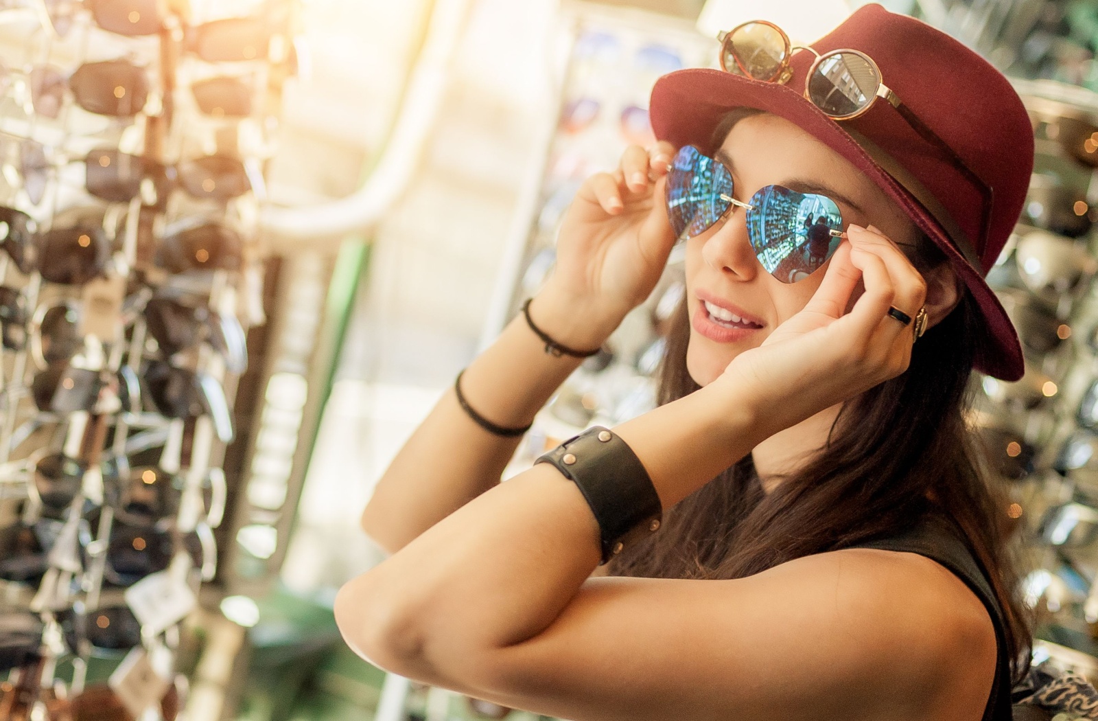 A smiling adult tries on a pair of heart-shaped sunglasses while looking for a new pair at an optometrist’s