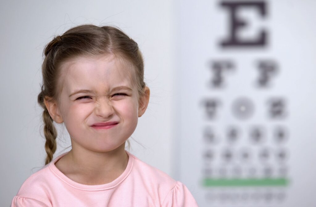 Child squinting in front of eye chart during vision test.