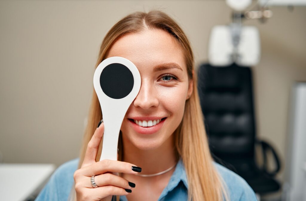 A smiling young adult gets an eye exam to see if they have amblyopia