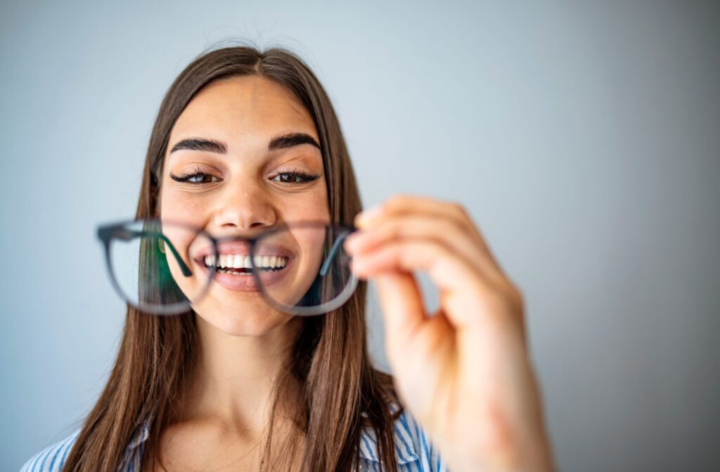 Person holding a pair of glasses in front of their face.
